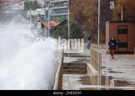 Cascais, Portugal. 03rd Januar 2022. Eine Welle stürzt auf einem Gehweg in der Nähe einiger Fußgänger an der Küste von Cascais ab. Portugal verzeichnete seit Beginn der Pandemie 1.577.784 Fälle und 19.071 Todesfälle im Zusammenhang mit Covid-19, so das Bulletin der Generaldirektion Gesundheit (DSG). (Foto von Jorge Castellanos/SOPA Images/Sipa USA) Quelle: SIPA USA/Alamy Live News Stockfoto