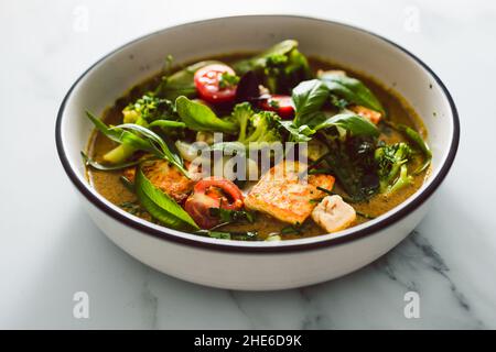 Veganes grünes Thai-Papyrus mit gebratenem seidigen Tofu-Brokkoli und Schneeerbsen, gekrönt mit frisch gepflückten Kräutern aus dem Garten, gesundes pflanzliches Speiserezept Stockfoto