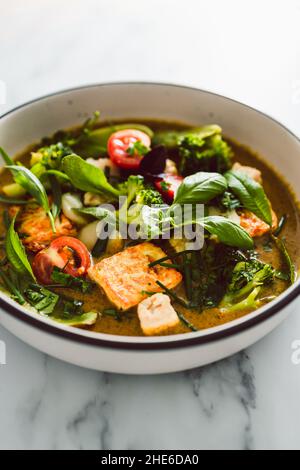 Veganes grünes Thai-Papyrus mit gebratenem seidigen Tofu-Brokkoli und Schneeerbsen, gekrönt mit frisch gepflückten Kräutern aus dem Garten, gesundes pflanzliches Speiserezept Stockfoto