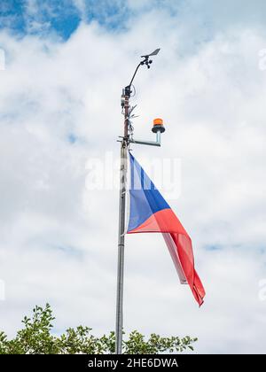 Tschechische Flagge auf hohem Fahnenmast mit drehenden Anemometer oder Wetterwindschieberpropeller und anderen Messanzeigen Stockfoto