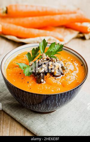 Schüssel Karottensuppe mit Sesam und Kürbiskernen und Petersilie garnieren Stockfoto
