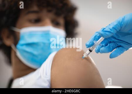 Schnitt einer Krankenschwester, die für einen männlichen Patienten einen Schuß in der Schulter machte Stockfoto