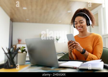 Lächelnde schwarze Frau mit schnurlosem Kopf und Mobiltelefon Stockfoto