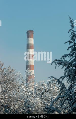 Industrieller alter hoher Ziegelkamin ohne Rauch, am blauen Himmel an einem frostigen Tag in Bulgarien. Stockfoto