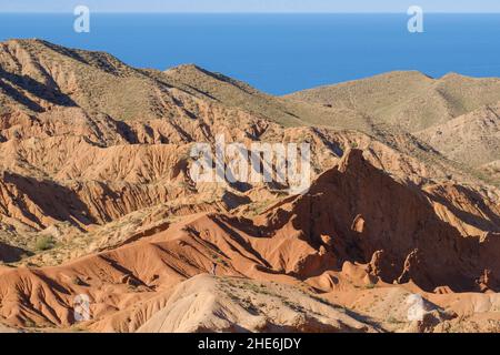 Man klettert den Berg in der Skazka Märchen Schlucht. Im Hintergrund der Issyk-Kul-See. Tosor, Kirgisistan Stockfoto