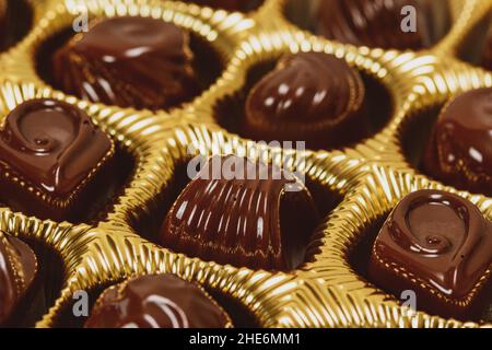 Sorte Art von Schokoladenpralinen in einer goldenen Schachtel. Nahaufnahme. Stockfoto
