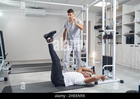 Mann, der Stretching-Übungen mit Fitnessgeräten macht Stockfoto