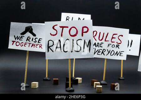 Konzept von Protest, Kundgebung, Demonstration. Plakate mit den Worten „Wir erheben uns zusammen“, „Stoppt Rassismus“, „Regeln sind für alle“. Stockfoto