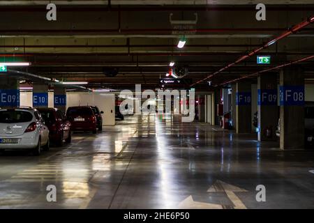 Parkhaus innen mit ein paar geparkten Autos. Tiefgarage in Bukarest, Rumänien, 2021 Stockfoto