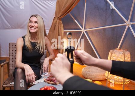 Mann entkorkt eine Flasche Wein für Frau im Restaurant Stockfoto