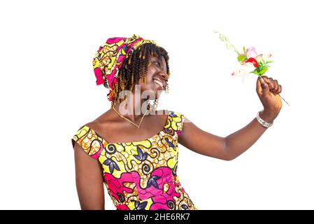 Schöne glückliche junge Frau, die traditionelle Lendenschurz trägt und Blumen lächelnd in der Hand hält. Stockfoto