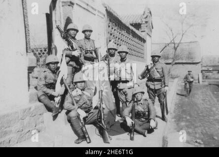 Zweiter Chinesisch-Japanischer Krieg, 1937-1945. Die Truppen der japanischen Marine Landing Force vom Marinestützpunkt Ryojun (Port Arthur), die in der Provinz Shandong stationiert sind, zeigen stolz eine Flagge, die von den chinesischen Truppen um Weihaiwei, um 1939, gefangen genommen wurde. Die kaiserliche japanische Marine marschierte Anfang 1938 in Shandong ein, eroberte lebenswichtige Küstenstädte und besetzte sie bis zur Kapitulation des japanischen Imperium im Jahr 1945. Stockfoto