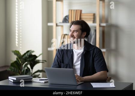 Glücklicher, gutaussehender junger Geschäftsmann, der in der Ferne schaut. Stockfoto