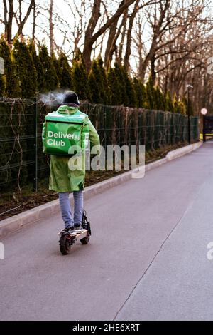 Krasnodar, Russland - Januar 7 2022: Food Delivery Junge Fahrt auf Elektroroller mit isothermen Beutel Stockfoto