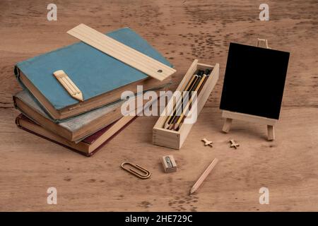 Vorlage für die Rückkehr zur Schule mit Büchern und einer leeren Tafel auf einem Holztisch Stockfoto