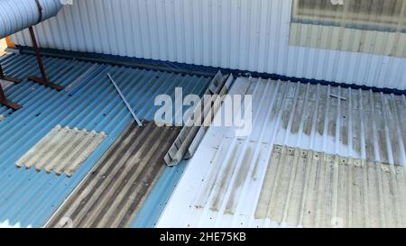 Inspektion des Dachs einer Metalldachfabrik, die das untere Dach und die Außenwand aus Metall, andere Metallablagerungen und Rohre auf dem Dach zeigt Stockfoto