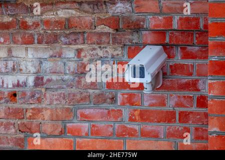 An der Backsteinwand des Gebäudes ist eine Außenüberwachungskamera angebracht. Stockfoto