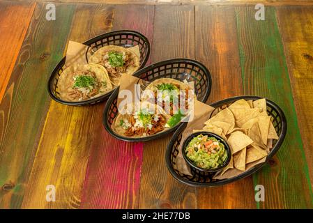 Verschiedene mexikanische Körbe mit Nachos mit Guacamole und verschiedenen Taco-Rezepten Stockfoto