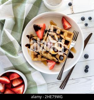 Blick von oben auf Waffeln mit frischem Obst, Schokoladensauce und Zucker. Stockfoto