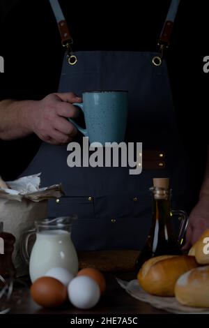 Arbeitend Bäcker Mann hält mit seiner Hand eine Tasse, in seiner Pause. Stockfoto