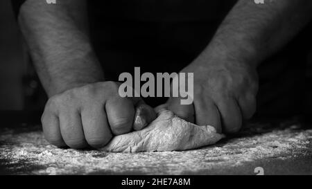 Frisches Brot in der Bäckerei backen, Hände von männlichem Teig auf Küchentisch mit Mehl kneten Stockfoto