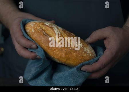 Bäcker hält Bio-Brot backen Brötchen in den Händen - ländliche Bäckerei, launisches Stillleben. Stockfoto