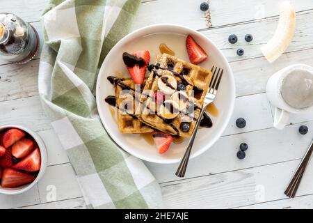 Hausgemachte Vollkorn-Waffeln mit Obst und Schokolade Nieselregen gekrönt. Stockfoto