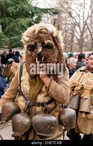 Kukeri-Tänzer mit aufwändigen Kostümen, großen Glocken und Masken tanzen beim traditionellen jährlichen Festival. Kukeri ist eine jahrhundertealte Tradition, die böse Geister vertreiben und gute einladen soll, die um den frühen Winter oder die Wintermitte abgehalten wird. Die Teilnehmer tragen übergroße Glocken, bestickte Kostüme und fantastische Masken, um am Winterritual teilzunehmen. Stockfoto