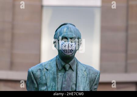 Glasgow, Schottland, Großbritannien. 9th. Januar 2022. Die Statue des ersten schottischen Ministers Donald Dewar oben in der Buchanan Street bekommt eine Gesichtsmaske und ein Schild mit den Aufschrift Bye Bye Freedom. Kredit: Skully/Alamy Live Nachrichten Stockfoto