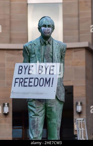 Glasgow, Schottland, Großbritannien. 9th. Januar 2022. Die Statue des ersten schottischen Ministers Donald Dewar oben in der Buchanan Street bekommt eine Gesichtsmaske und ein Schild mit den Aufschrift Bye Bye Freedom. Kredit: Skully/Alamy Live Nachrichten Stockfoto