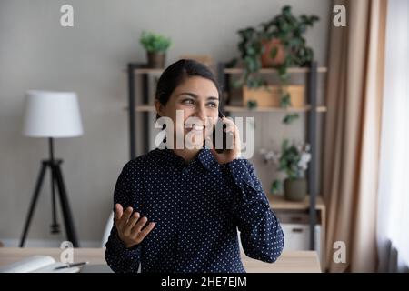 Glückliche, tausendjährige indische Geschäftsfrau, die am Handy spricht Stockfoto