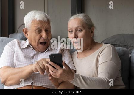 Glücklich überraschte das alte Paar, das die Nachricht mit unglaublichen Nachrichten las. Stockfoto