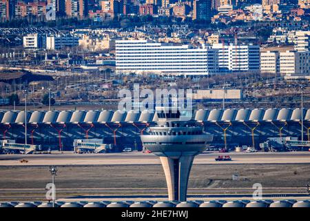 Madrid, Spanien - 31. Dezember 2021: Kontrollturm des Flughafens Adolfo Suarez Madrid-Barajas gegen das Stadtbild. Stockfoto