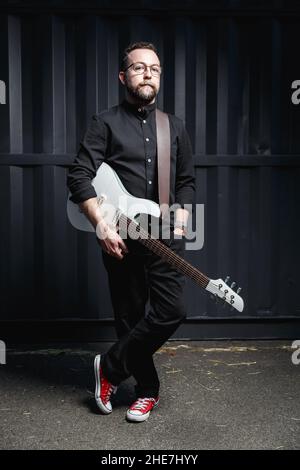 Porträt eines männlichen Gitarristen mit E-Gitarre in schwarzer Kleidung. Rockmusiker Charakter Konzept Stockfoto