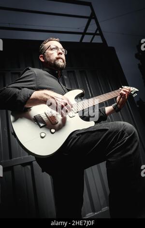Porträt eines männlichen Gitarristen mit E-Gitarre in schwarzer Kleidung. Rockmusiker Charakter Konzept Stockfoto