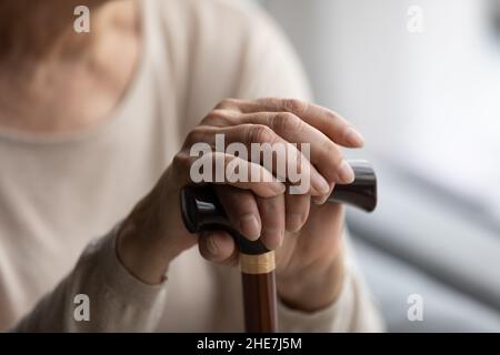 Nahaufnahme Fokus auf gefaltete faltige weibliche Hände auf Holzstock. Stockfoto