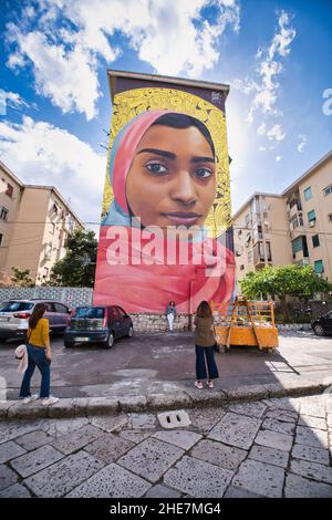 Drei junge Touristen halten ein Bild, das unter Bakitha ein schönes Wandbild in Palermo posiert Stockfoto