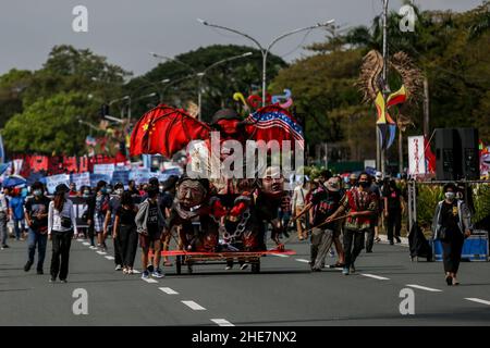 Menschenrechtsaktivisten tragen Schilder und bieten Blumen an, um an gefallene Helden im Gedenken an den Internationalen Menschenrechtstag 73rd in Quezon City, Metro Manila, zu erinnern. Das Denkmal ehrt die Märtyrer und Helden, die gegen die 21-jährige Diktatur des ehemaligen Präsidenten Ferdinand Marcos kämpften. Philippinen. Stockfoto