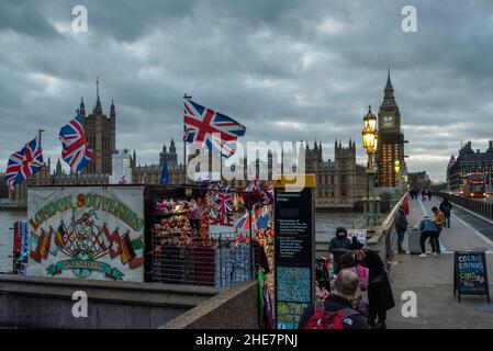 London, Großbritannien. 9. Januar 2022. Wetter in Großbritannien – Union Jack-Flaggen flattern im Wind, während die Houses of Parliament in der Abenddämmerung mit eingeschalteten Straßenlaternen auf der Westminster Bridge zu sehen sind. Kredit: Stephen Chung / Alamy Live Nachrichten Stockfoto