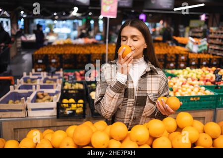 Frau riecht orange beim Einkaufen im Supermarkt Stockfoto
