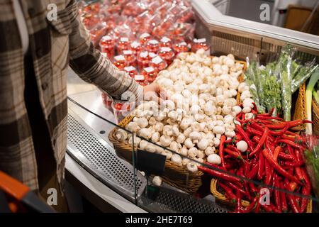 Die Frau wählt in der Gemüseabteilung des Supermarkts Champignons Stockfoto