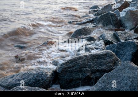 Wellen brechen über Felsen der Meeresverteidigung in Skegness, Lincolnshire, Großbritannien Stockfoto