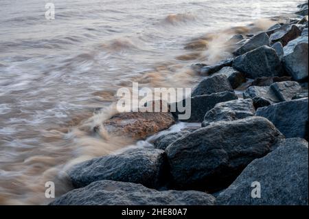 Wellen brechen über Felsen der Meeresverteidigung in Skegness, Lincolnshire, Großbritannien Stockfoto