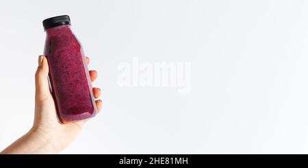 Eine Frau hält ein Glas mit Beerenmoothies auf weißem Hintergrund in der Hand. Banner Stockfoto