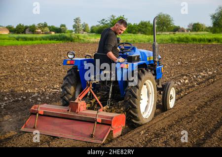 Cherson Oblast, Ukraine - 29. Mai 2021: Seniorbauer arbeitet auf dem Feld auf einem Traktor. Saisonarbeiter. Lockern, Anbau. Pflügen. Einstellung eines Stockfoto