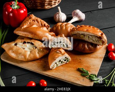 Leckere Torten auf einem Schneidebrett. Komposition auf schwarzem Hintergrund mit Zutaten. Stockfoto