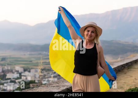 Glückliche Frau mit der Flagge der Ukraine in den Bergen zu bleiben Stockfoto