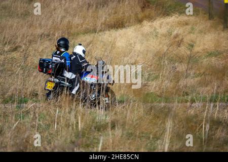 Motorradfahrer und Sozius auf einem BMW R1200 GS Motorrad, das durch die Winterlandschaft fährt Stockfoto