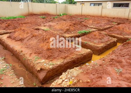 Ausgegraben Fundamente eines Gebäudes, das gebaut werden soll. Die Gräben der Fundamente sind nach dem Regen mit Schlammwasser gefüllt. Stockfoto