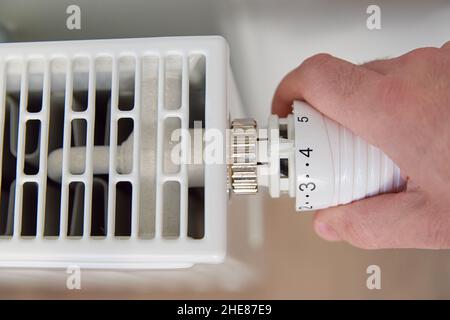 Die Temperatur am Heizkörper-Thermostat von Hand einstellen und den Heizkörper-Regler drehen, um die Wärme zu Hause zu steuern Stockfoto